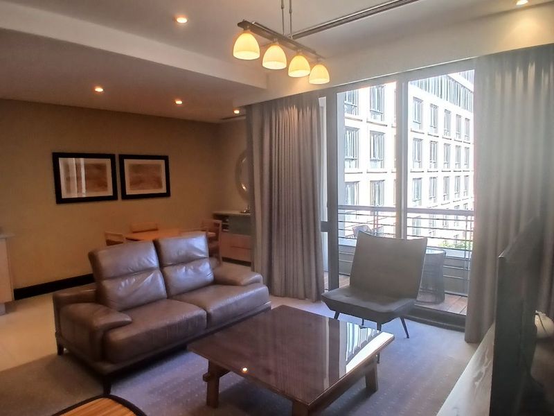 A well-maintained living room featuring recessed lighting, central air conditioning, and large sliding glass doors leading to a private balcony.