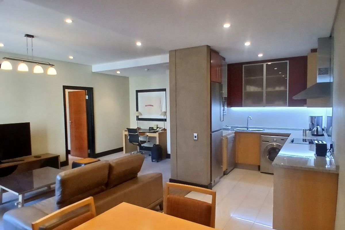 Open-plan living area featuring a modern kitchen with built-in cabinetry, integrated appliances, and a dedicated workspace, finished with tiled flooring and recessed lighting.