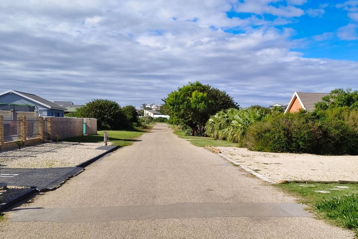 A clear street view showing the paved road, surrounding residential properties, and established landscaping in a quiet neighborhood setting.