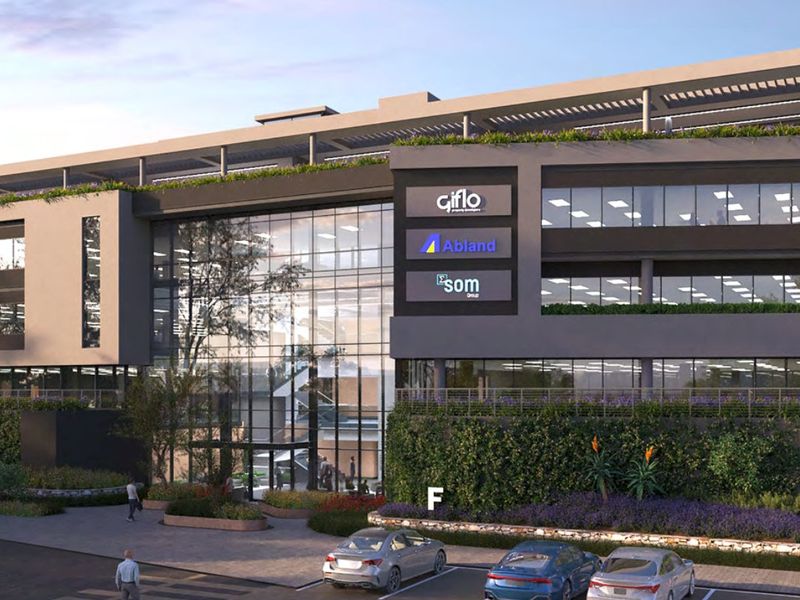 Modern commercial office building featuring a prominent glass facade, integrated green walls, and a rooftop terrace with professional landscaping.