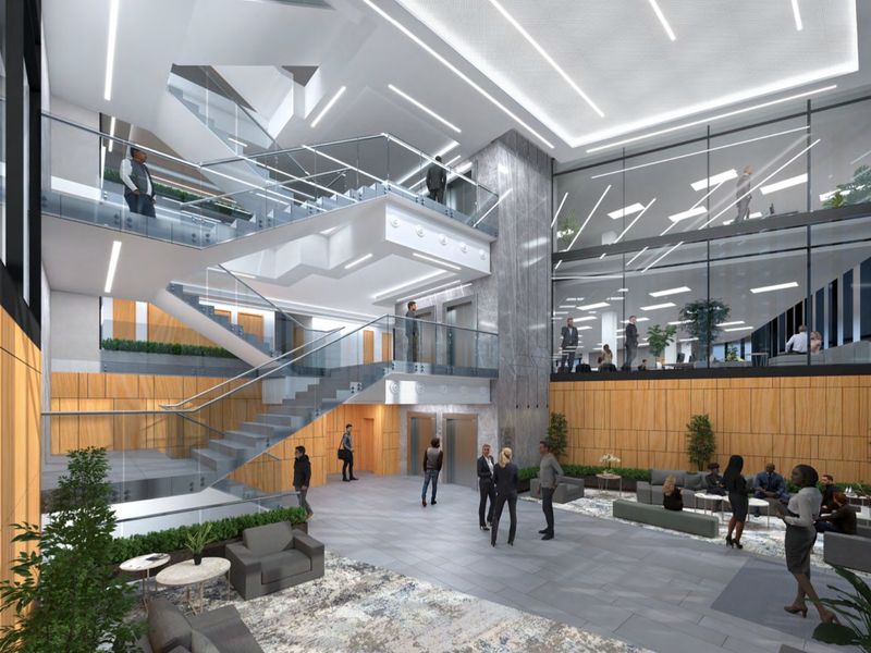 Modern commercial building lobby featuring a grand staircase, glass elevator shafts, stone accents, and expansive glass partitions overlooking office levels.