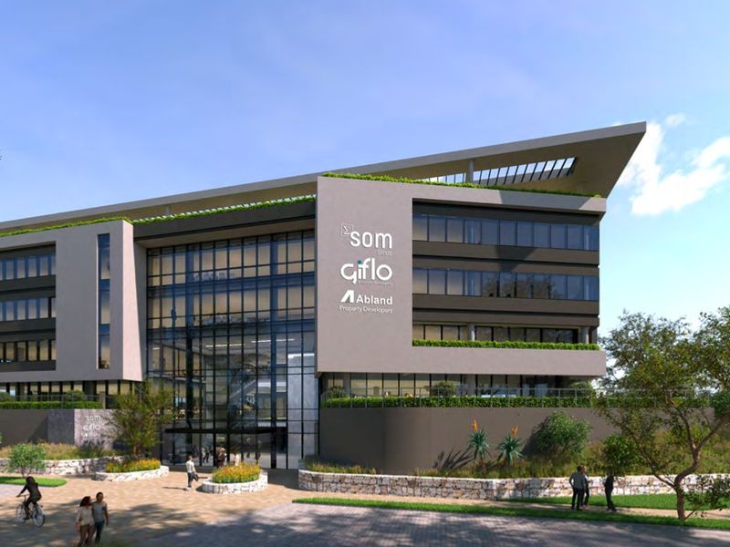 A modern commercial office building featuring a striking glass facade, contemporary architectural design, and landscaped surroundings.