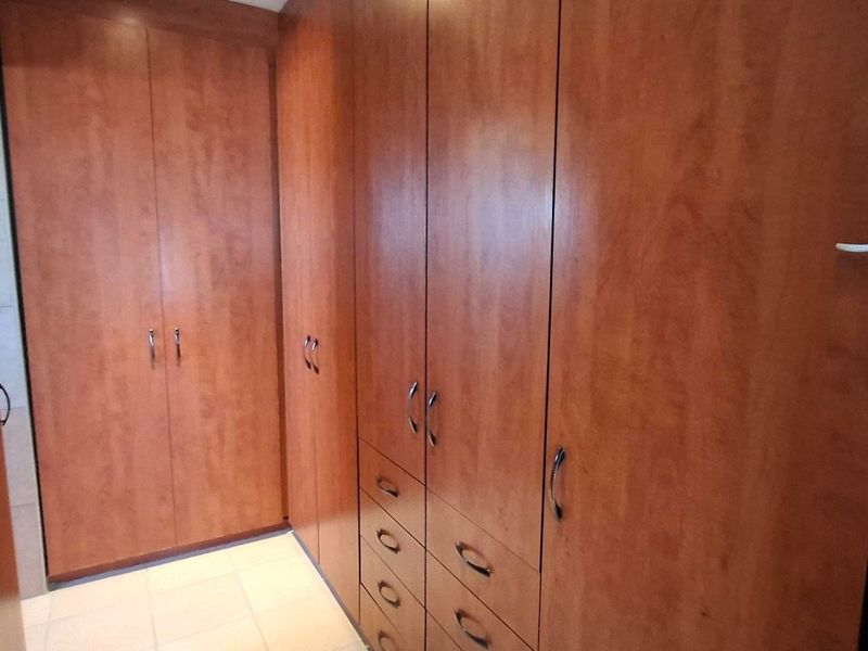 A functional bedroom area featuring extensive built-in wooden cabinetry and tiled flooring, providing ample storage space.