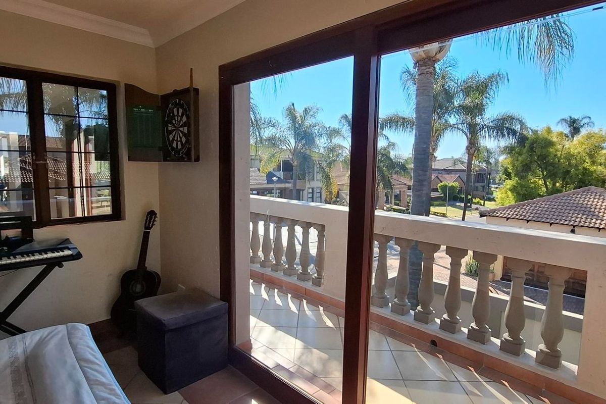 Bedroom featuring sliding glass doors opening onto a private balcony with stone balustrade and views of the surrounding neighborhood.