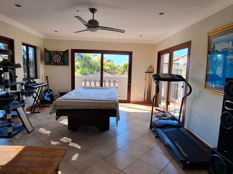 Spacious living area featuring tiled flooring, recessed lighting, a ceiling fan, and multiple sliding glass doors providing access to the outdoor balcony.