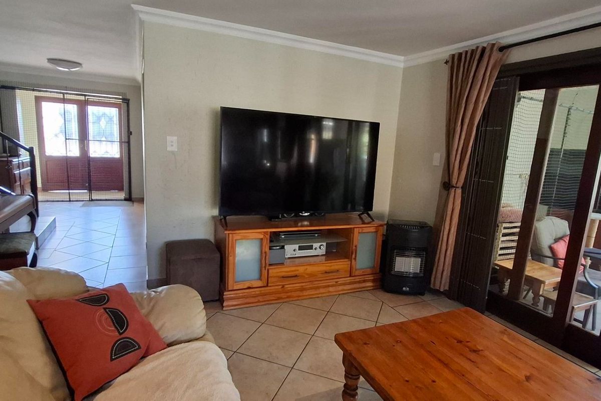 A comfortable living room featuring tiled flooring and large sliding glass doors that provide access to an outdoor patio area.