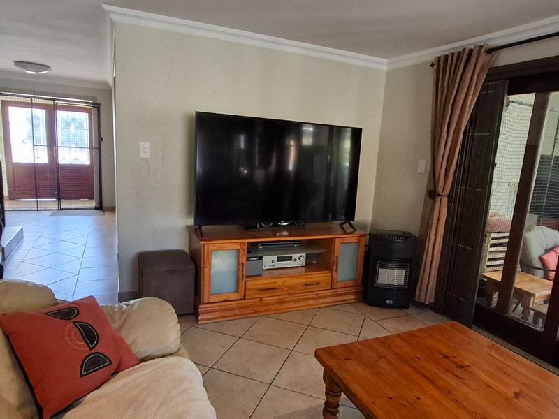 A comfortable living room featuring tiled flooring and large sliding glass doors that provide access to an outdoor patio area.