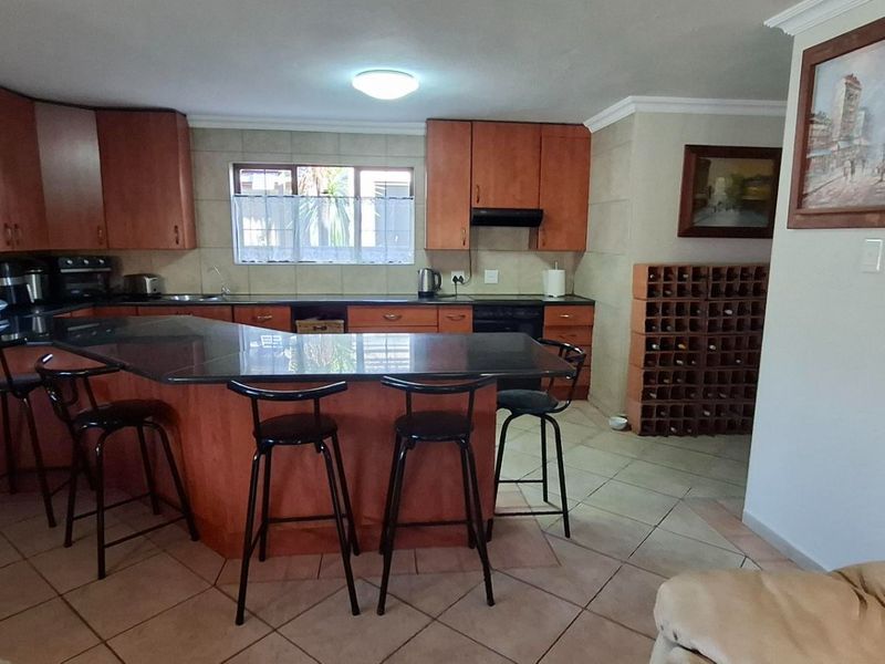 Spacious kitchen featuring wooden cabinetry, granite countertops, a breakfast bar, and a built-in wine rack, offering functional storage and preparation space.