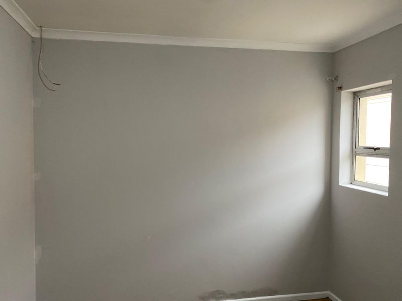 An empty bedroom featuring neutral walls, a window, and exposed electrical wiring requiring finishing.
