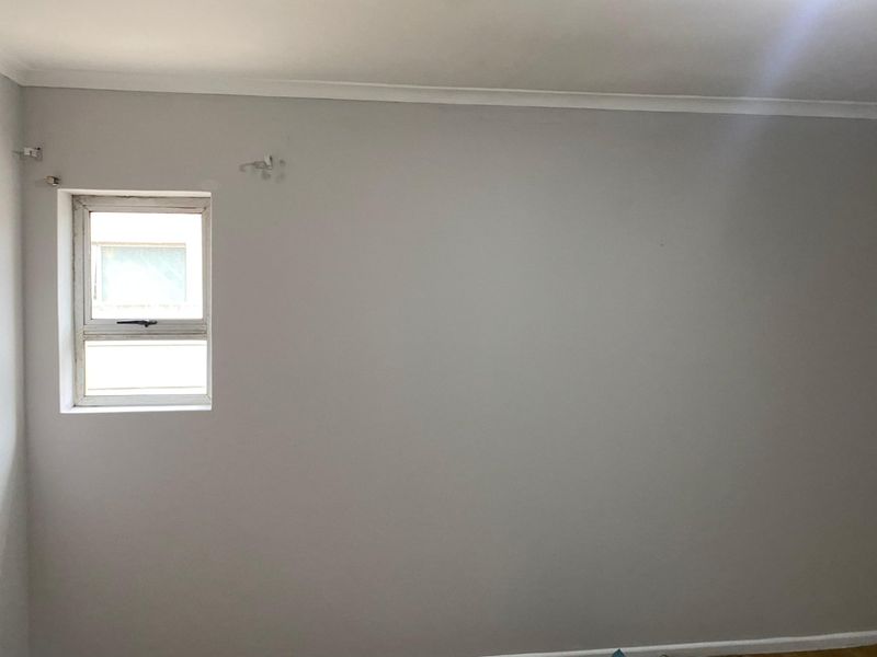 A vacant bedroom featuring a single casement window and simple cornice detailing, providing a blank canvas for interior design.