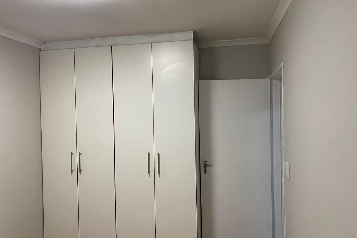 A clean, neutral bedroom featuring white built-in cupboards and coving, providing a blank canvas for personalization.