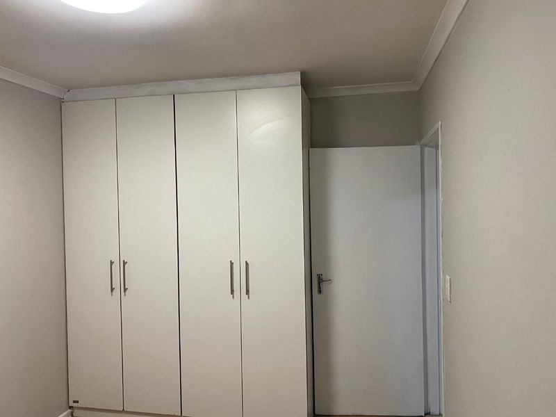 A clean, neutral bedroom featuring white built-in cupboards and coving, providing a blank canvas for personalization.