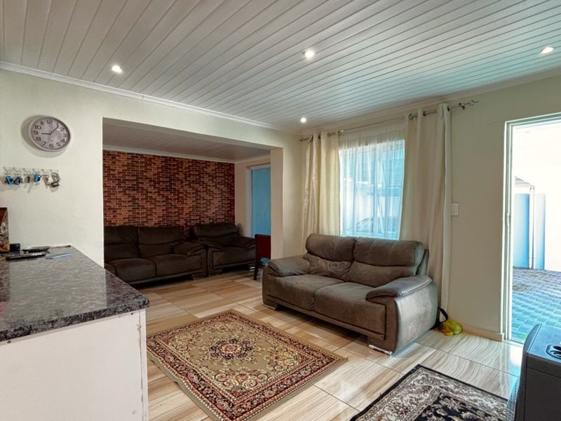 Open-plan living area featuring tiled floors, a tongue and groove ceiling, and an exposed brick accent wall, with direct access to an outdoor space.