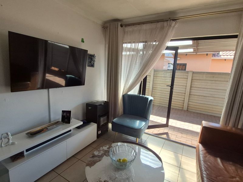 A living room featuring tiled flooring and a sliding glass door providing direct access to an outdoor patio area.