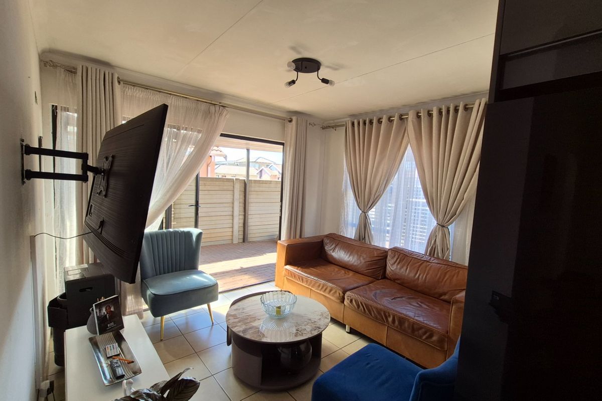 A living room featuring tiled flooring and a sliding glass door providing access to an outdoor patio area.