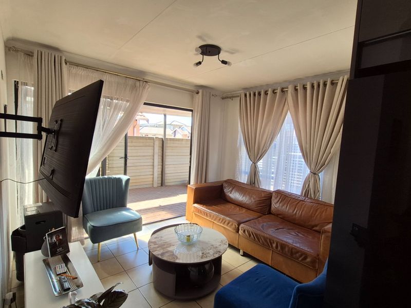 A living room featuring tiled flooring and a sliding glass door providing access to an outdoor patio area.