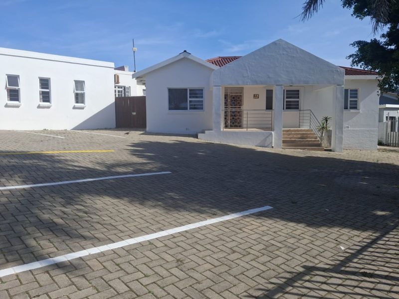 Front exterior view of a commercial property featuring a paved parking area and a covered entrance porch with security gate.