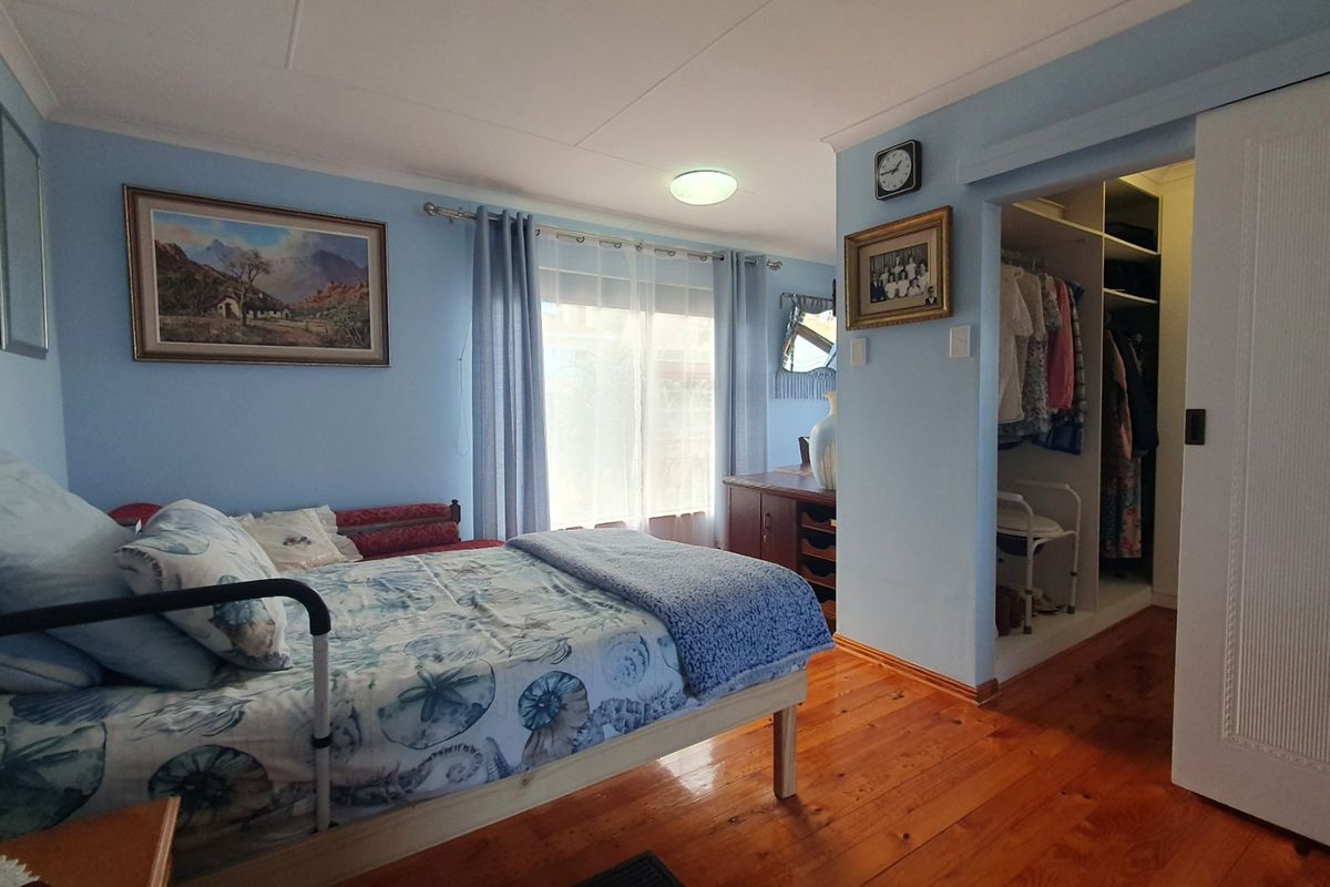 A bedroom featuring polished hardwood flooring, a built-in wardrobe with a sliding door, and natural light from the window.