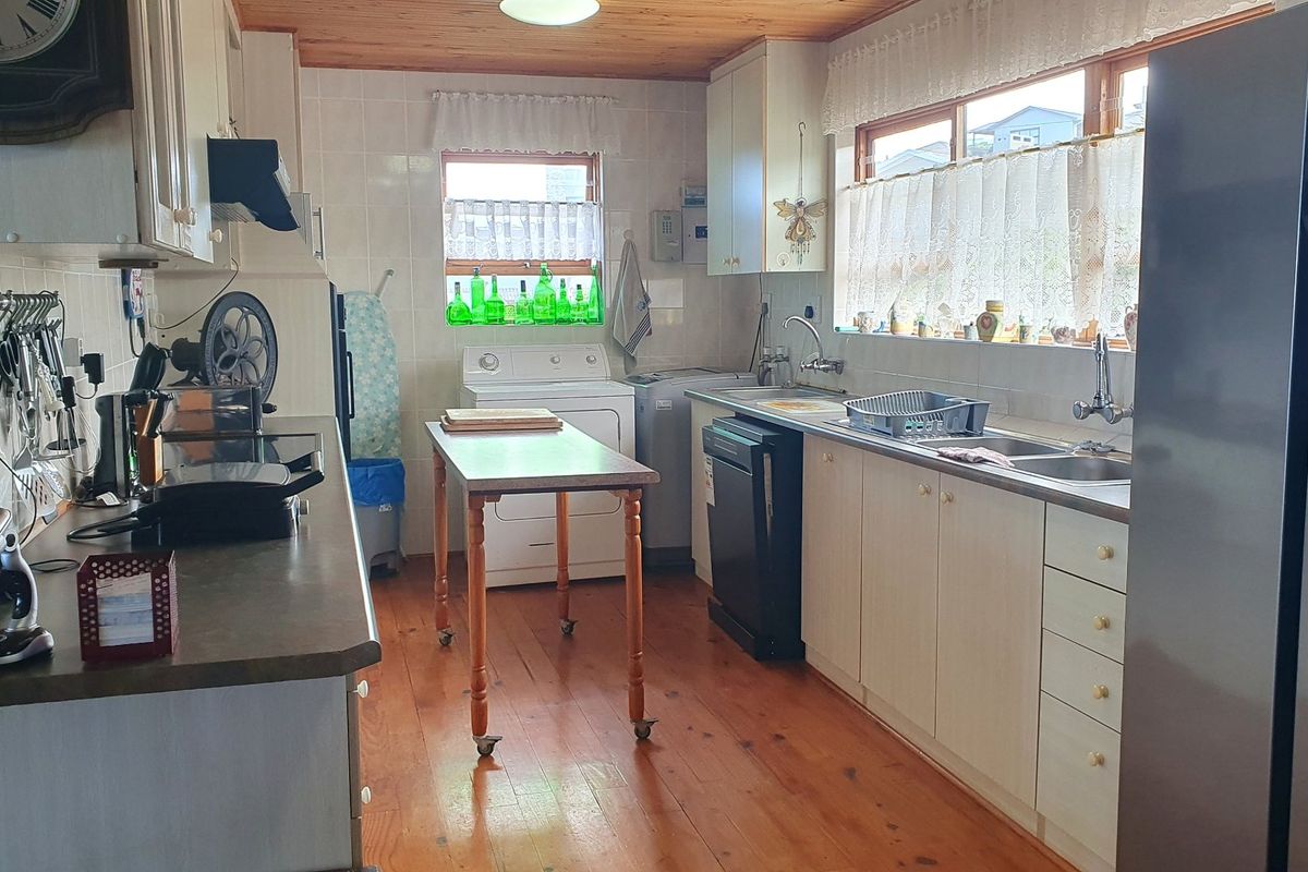 A functional kitchen featuring timber flooring, wood-paneled ceiling, laminate cabinetry, and a double basin sink with tiled splashbacks.