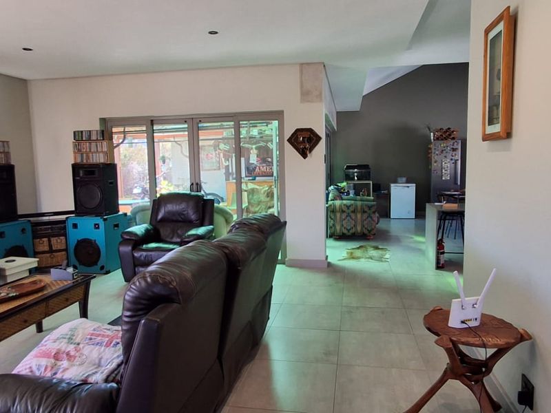 Spacious open-plan living area featuring neutral tiled flooring, recessed lighting, and large sliding glass doors providing access to the outdoor space.