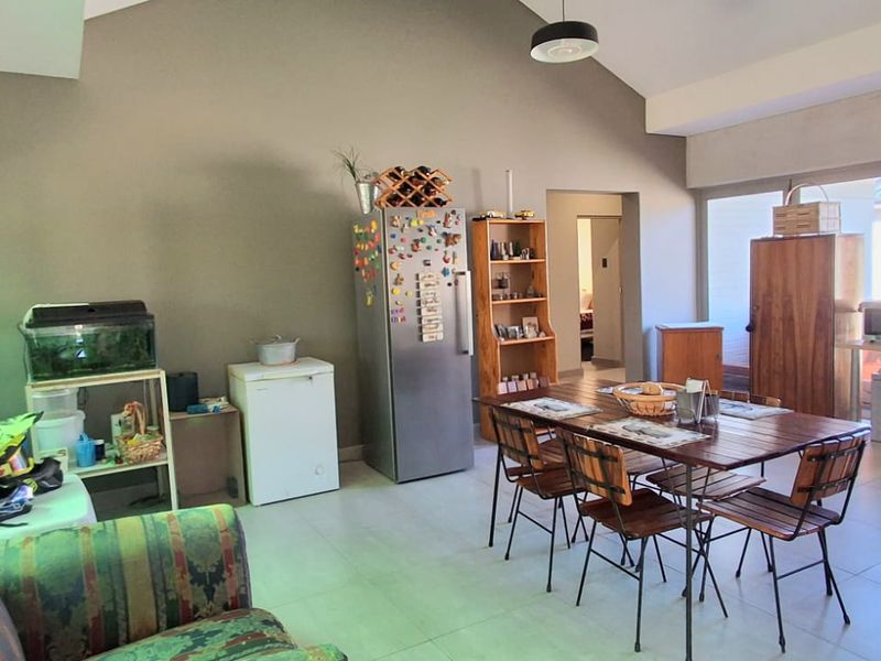 Spacious open-plan living and dining area featuring vaulted ceilings, tiled flooring, and large sliding glass doors providing ample natural light.