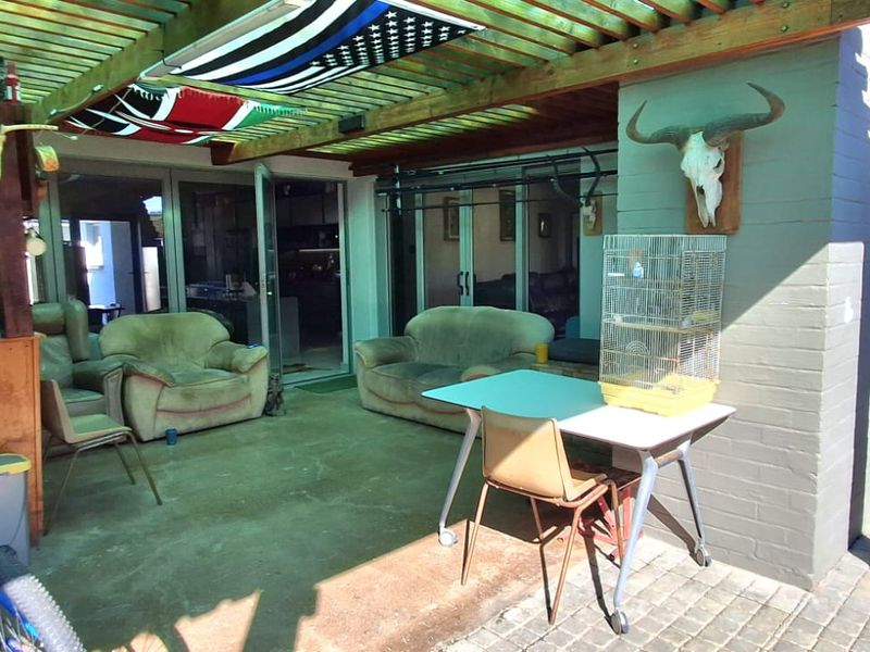 A covered outdoor patio area featuring a timber pergola, brick pillar, and sliding glass door access to the main living space.