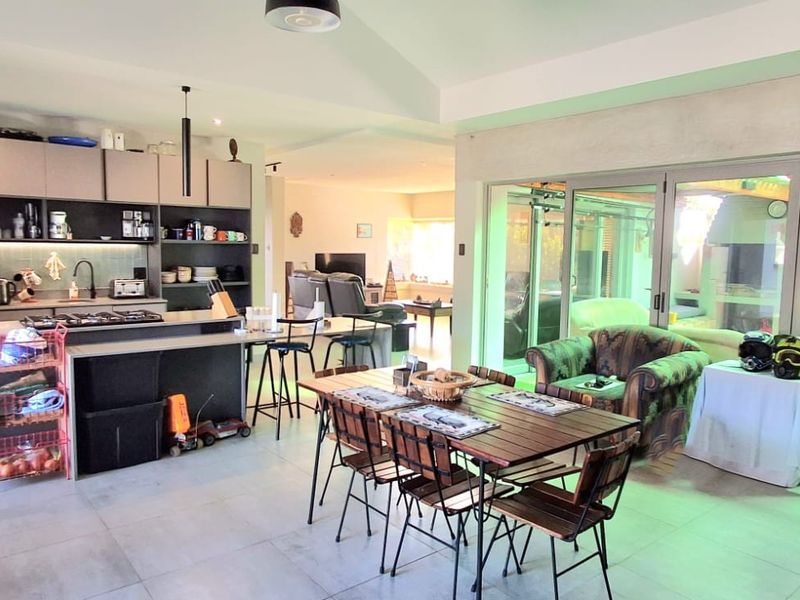 Spacious open-plan kitchen and dining area featuring modern cabinetry, a central island with gas hob, and large sliding doors leading to the outdoor space.
