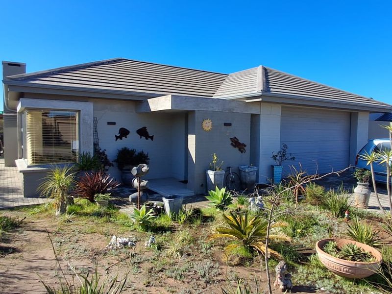 Front elevation of a single-story residential home featuring a tiled roof, integrated garage, and paved driveway with established garden landscaping.