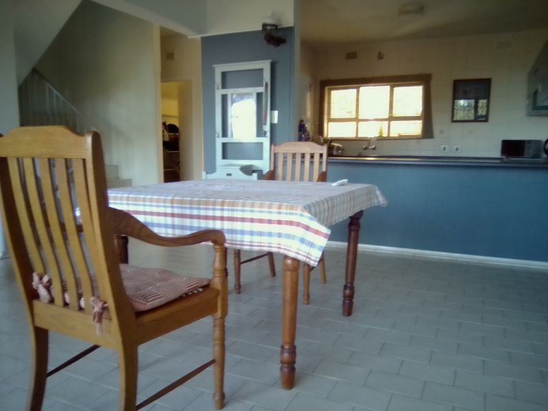 Open plan living and dining area featuring tiled flooring, a kitchen breakfast bar, and an adjacent staircase leading to the upper level.