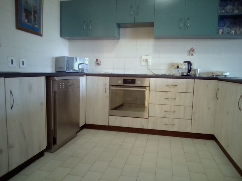 A functional kitchen featuring light-toned laminate cabinetry, a built-in oven, tiled splashbacks, and tiled flooring, offering a practical layout for daily use.
