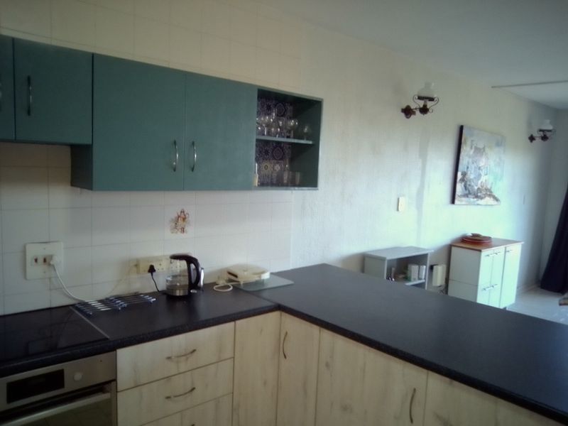 A functional kitchen area featuring built-in cabinetry, dark laminate countertops, a built-in oven, and a ceramic hob with a tiled backsplash.