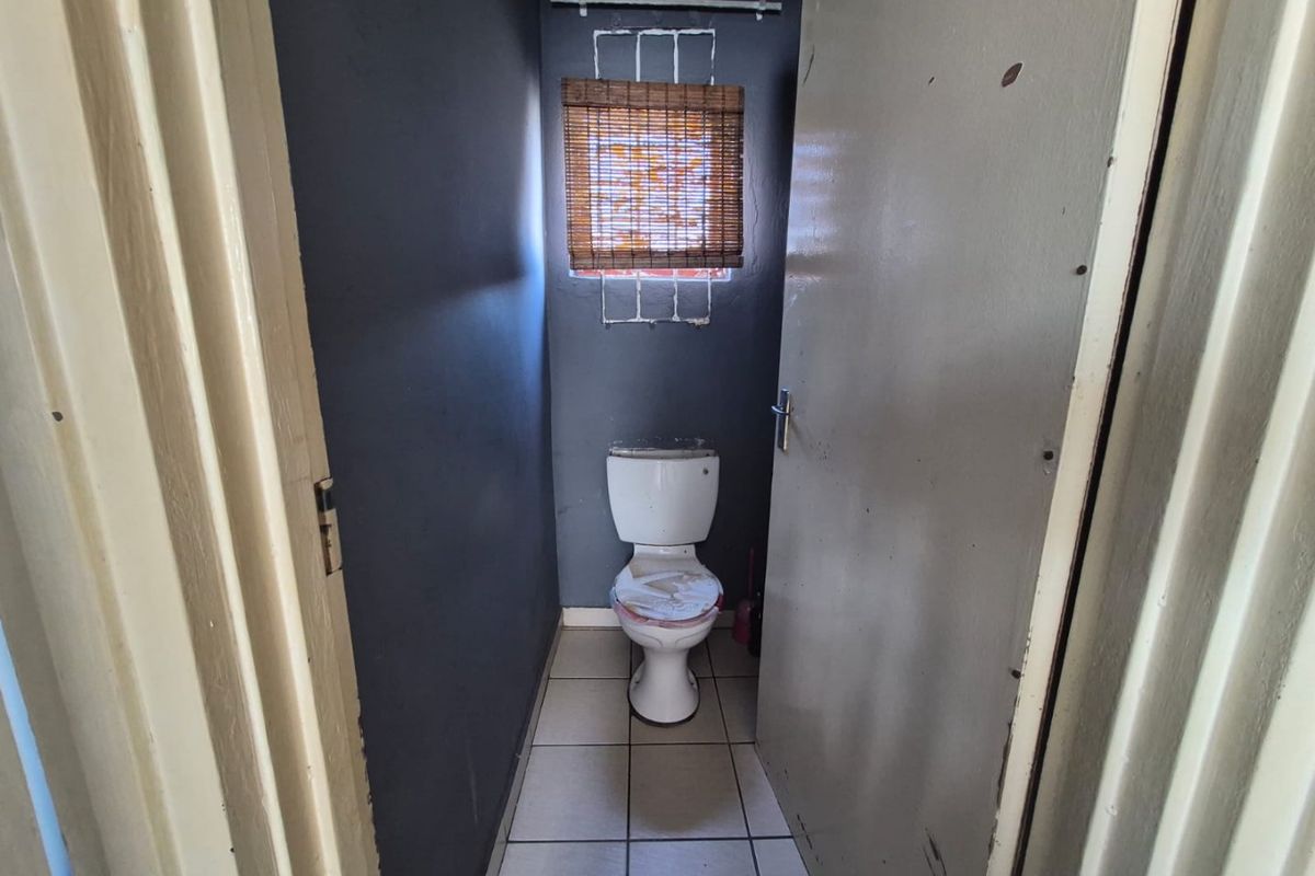 A small, functional bathroom featuring tiled flooring and a standard toilet, requiring cosmetic updates to improve its overall condition and appeal.