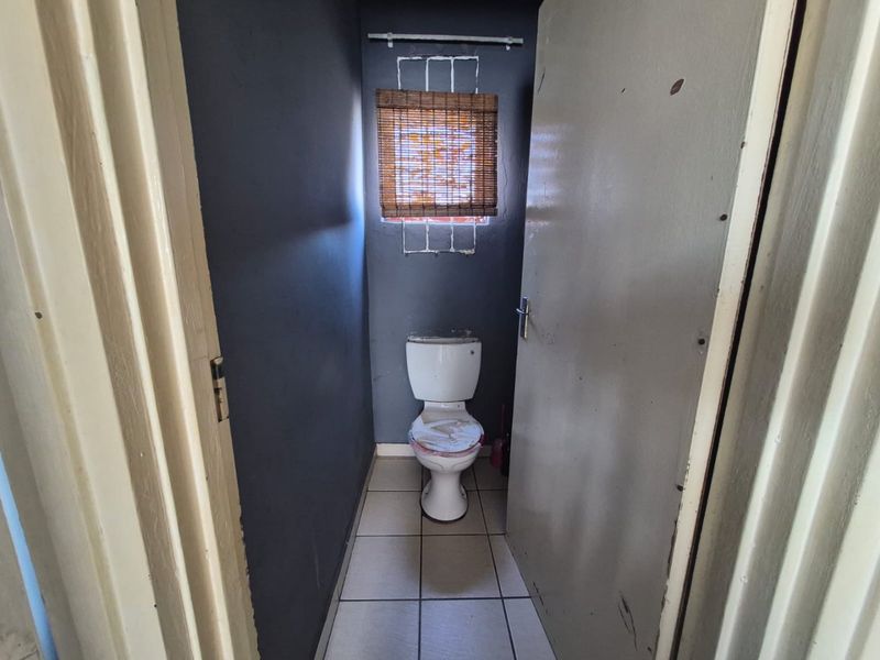 A small, functional bathroom featuring tiled flooring and a standard toilet, requiring cosmetic updates to improve its overall condition and appeal.