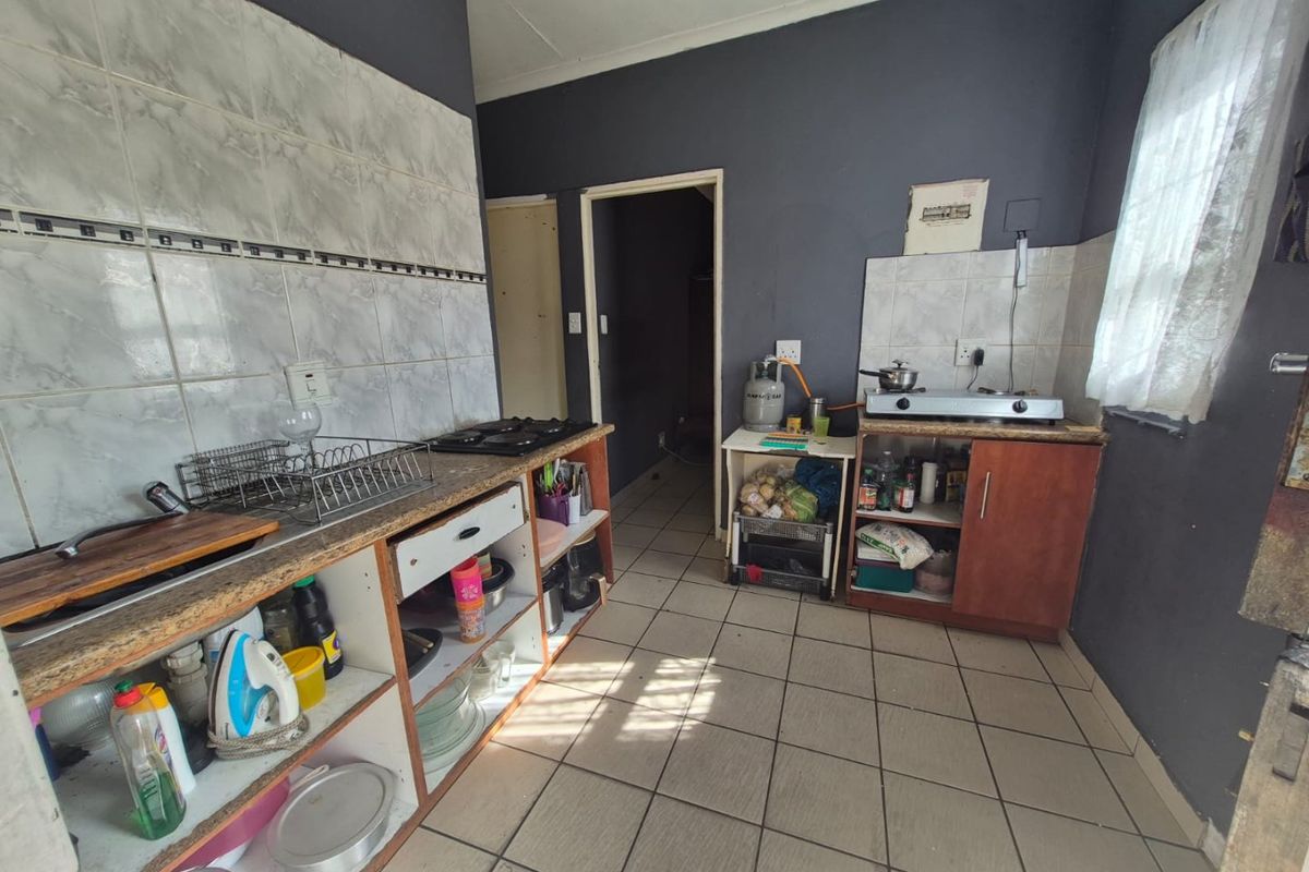 A functional kitchen featuring tiled flooring, a tiled splashback, and built-in cabinetry with a gas hob, offering potential for modernization and cosmetic updates.