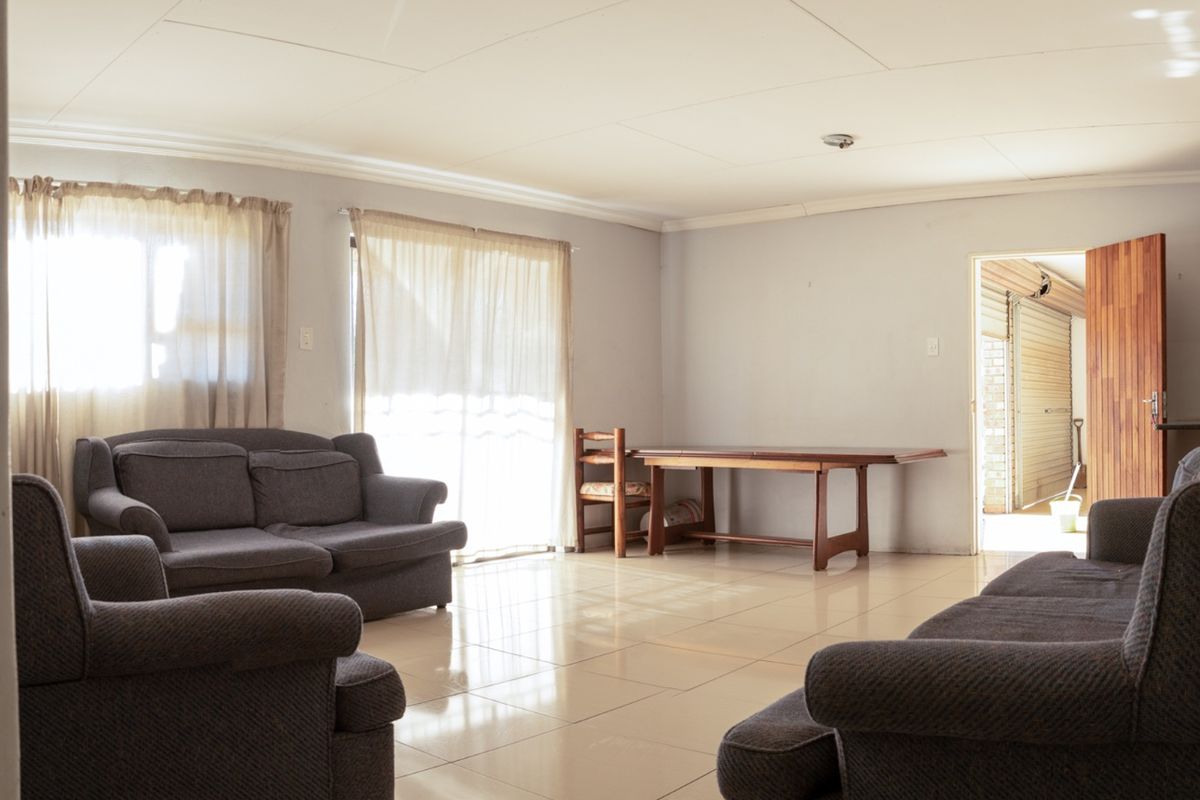 Spacious living area featuring neutral tiled flooring and natural light through sliding glass doors, providing a functional and open layout.