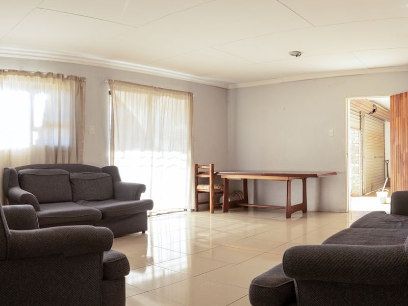 Spacious living area featuring neutral tiled flooring and natural light through sliding glass doors, providing a functional and open layout.