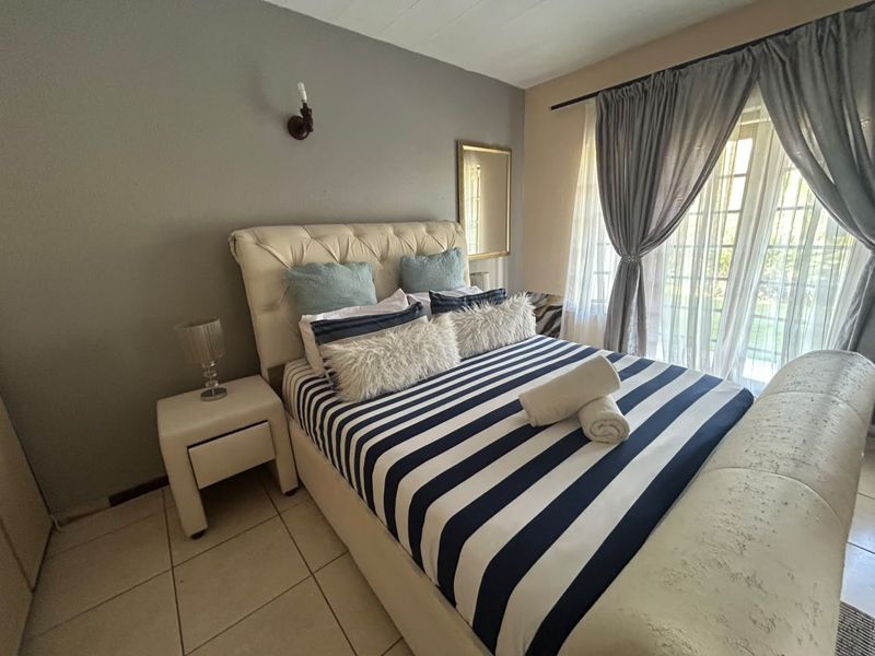 A bedroom featuring tiled flooring, a wall-mounted light fixture, and a sliding glass door providing access to the exterior.