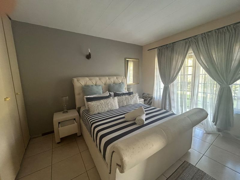 A bedroom featuring tiled flooring, a built-in wardrobe, and a sliding glass door providing natural light and access to the exterior.