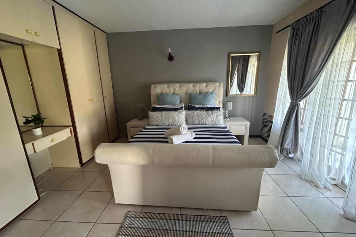A bedroom featuring built-in cupboards, tiled flooring, and a sliding door providing access to the exterior.