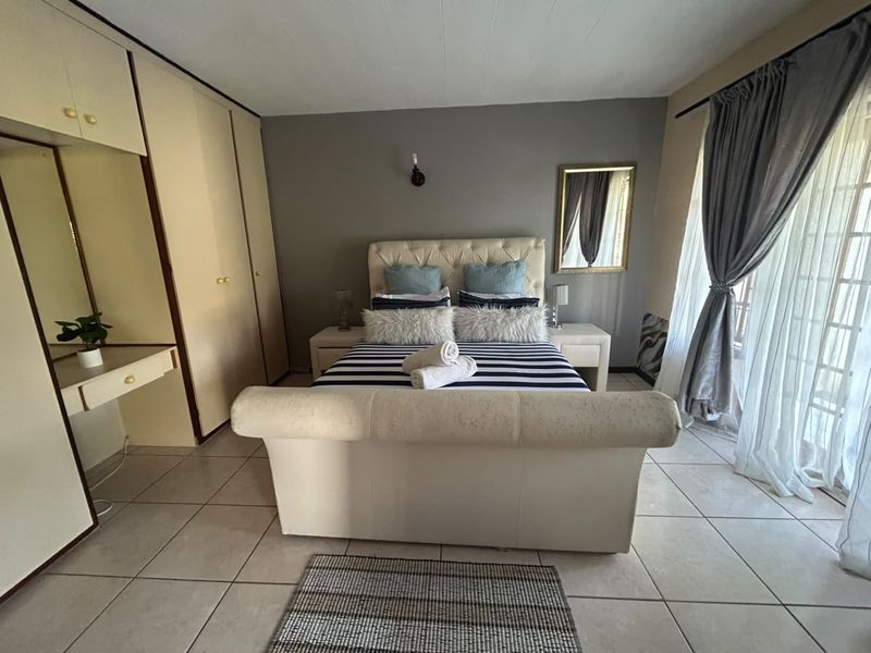 A bedroom featuring built-in cupboards, tiled flooring, and a sliding door providing access to the exterior.