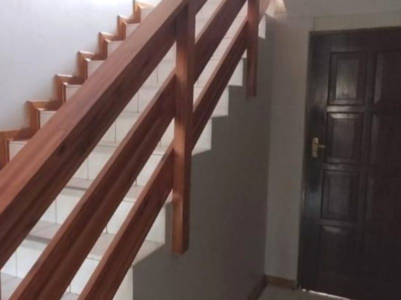 Entrance area featuring a tiled floor, a solid wood door, and a wooden staircase with a matching handrail.