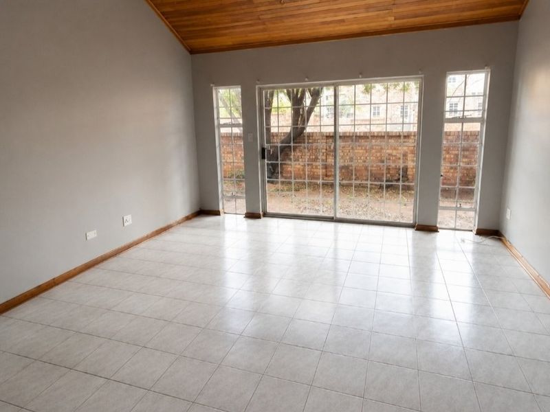 Spacious living area featuring tiled floors, a vaulted timber-clad ceiling, and large sliding glass doors providing access to the rear garden.