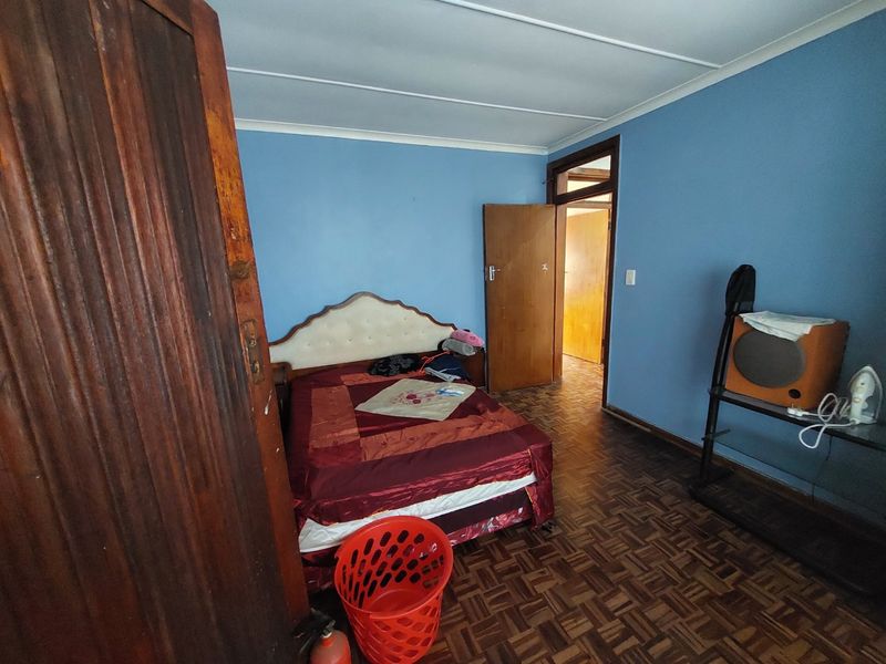 A bedroom featuring classic parquet flooring and blue painted walls, providing a functional space with traditional architectural elements.