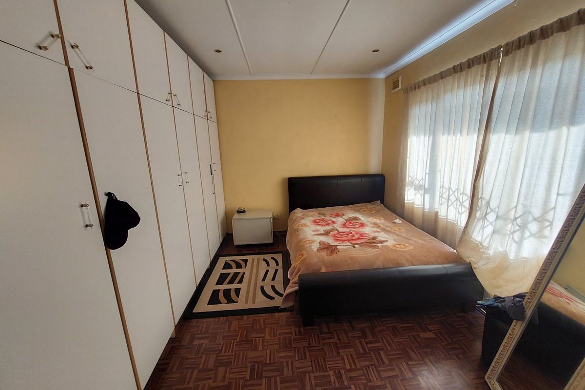 A bedroom featuring parquet flooring, built-in cupboards, and recessed ceiling lighting, offering a functional space with potential for modern updates.