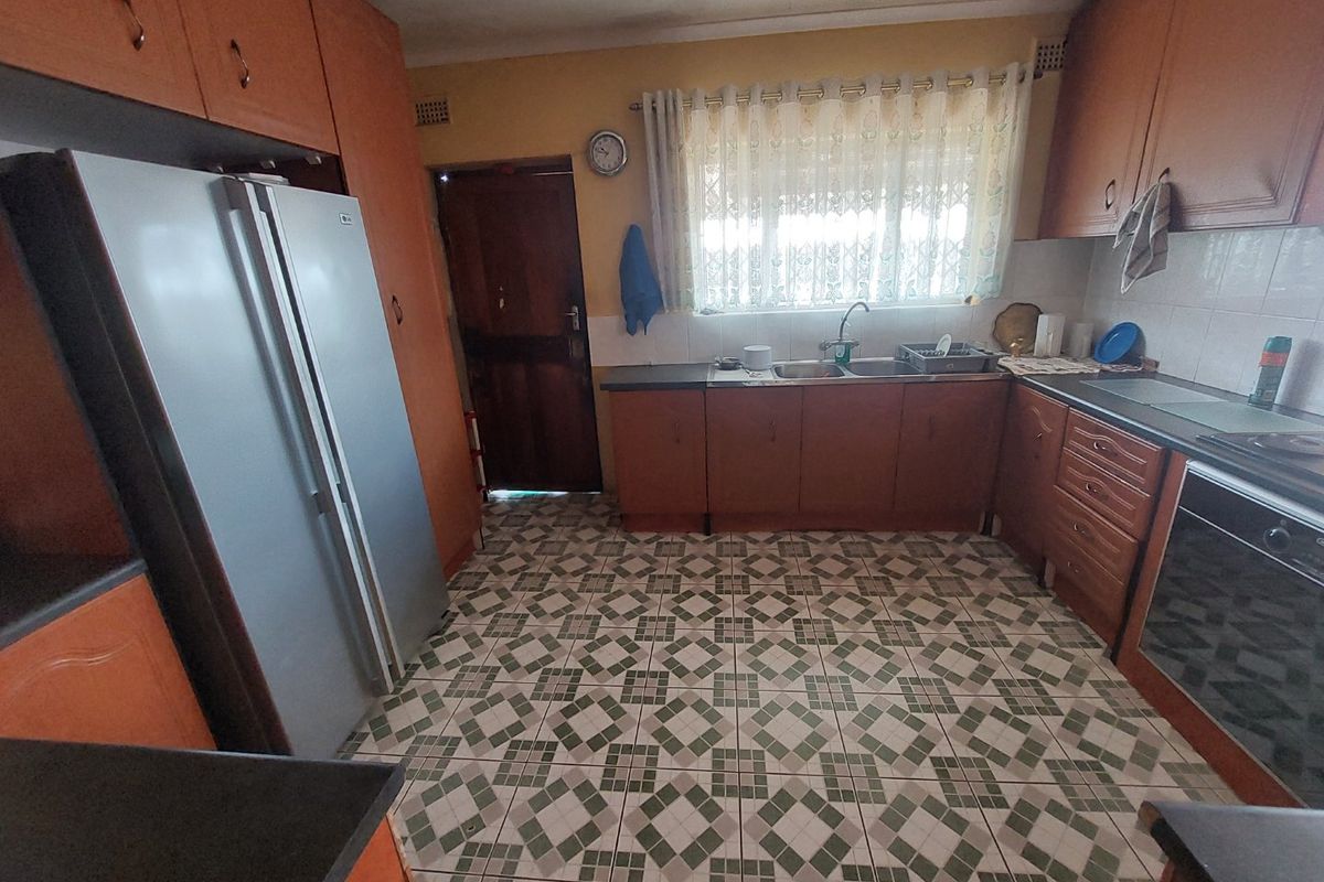 A functional kitchen featuring wooden cabinetry, tiled flooring, a double sink, and built-in oven, offering potential for a modern renovation.