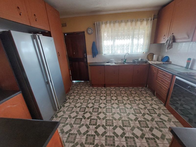A functional kitchen featuring wooden cabinetry, tiled flooring, a double sink, and built-in oven, offering potential for a modern renovation.