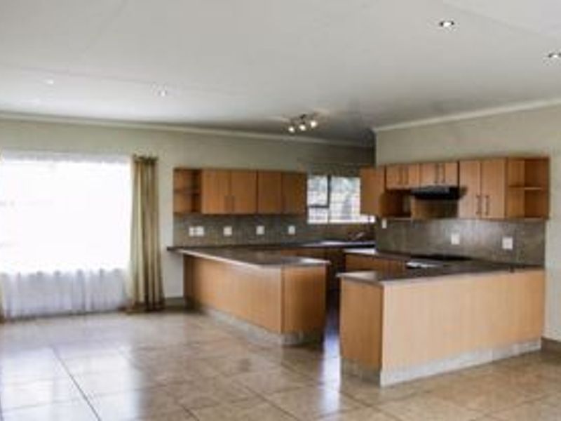 Spacious open-plan kitchen and living area featuring light wood cabinetry, tiled flooring, and recessed lighting, offering a functional and versatile layout.