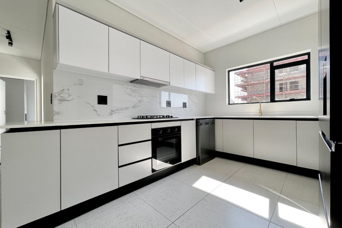 Modern kitchen featuring sleek white cabinetry, marble-look splashback, integrated gas hob, built-in oven, and high-quality tiled flooring in a bright, clean space.