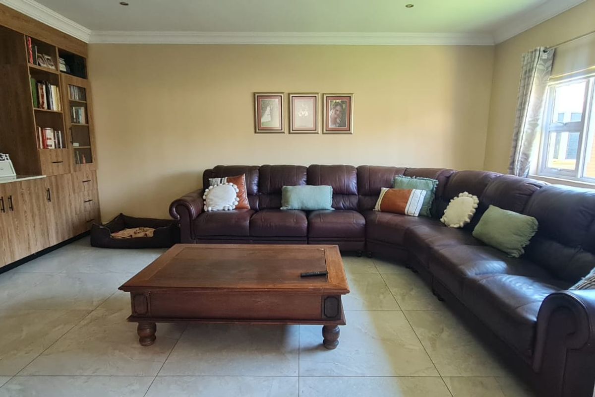 A spacious living room featuring large format floor tiles, recessed lighting, and extensive built-in cabinetry for storage and media display.