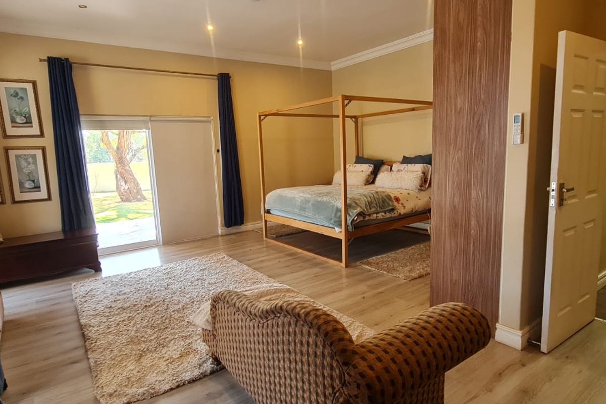 Spacious bedroom featuring laminate flooring, recessed lighting, and a sliding glass door providing direct access to the garden area.